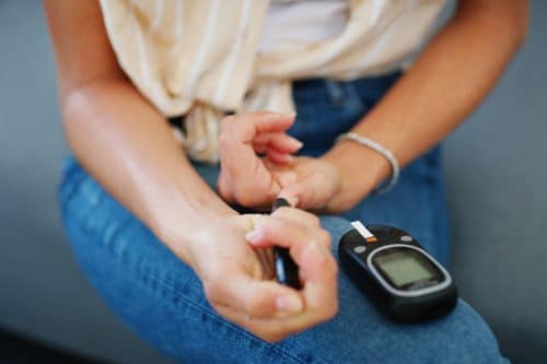 Cropped shot of a woman checking her blood sugar at home