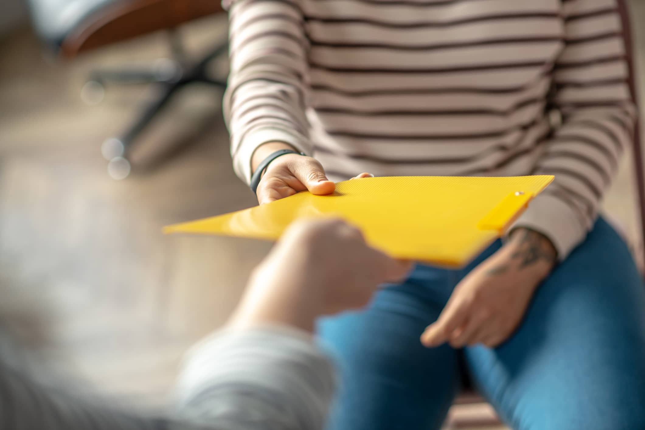 Yellow folder. Close up picture of womans hand passing the folder