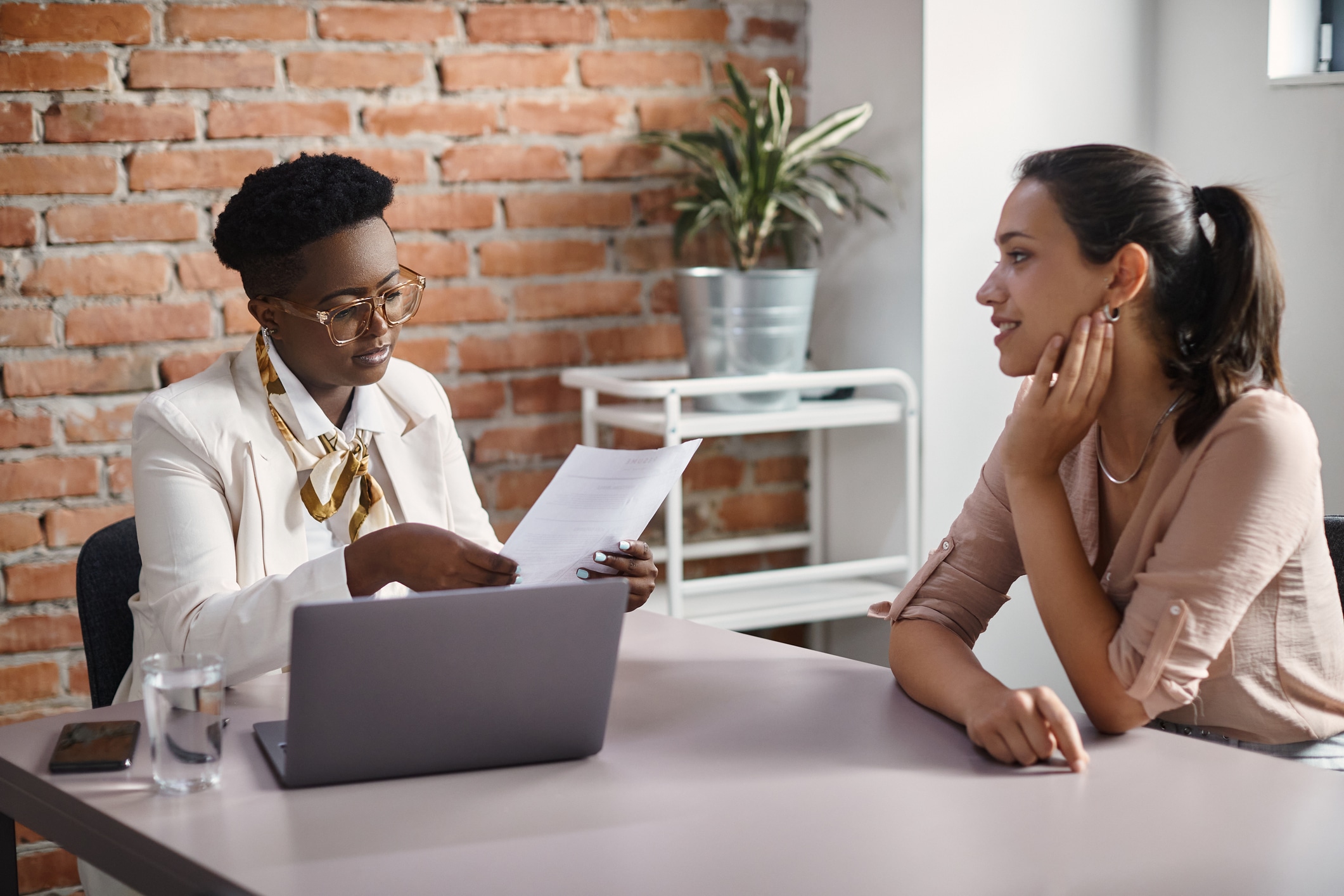 African American human resource manager talking to job candidate while reading her CV during a meeting in the office.