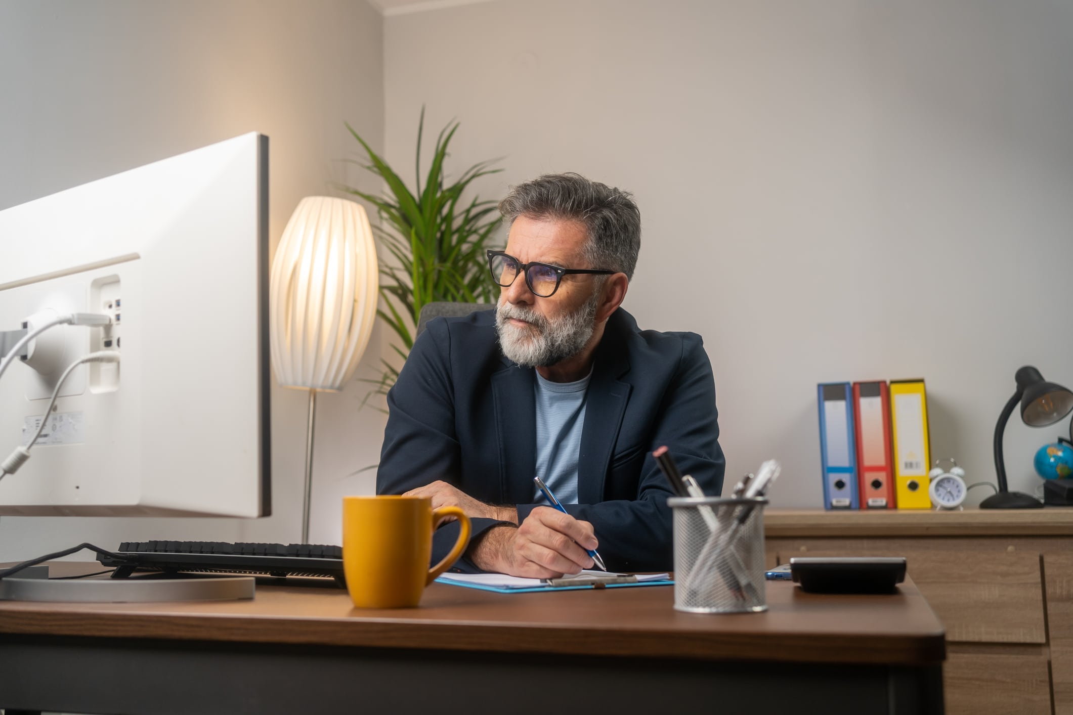 Office worker lifestyle people. One man writing notes on book and using computer. Indoor home office workplace lifestyle people. Excited adult man, happy with the income his business made.