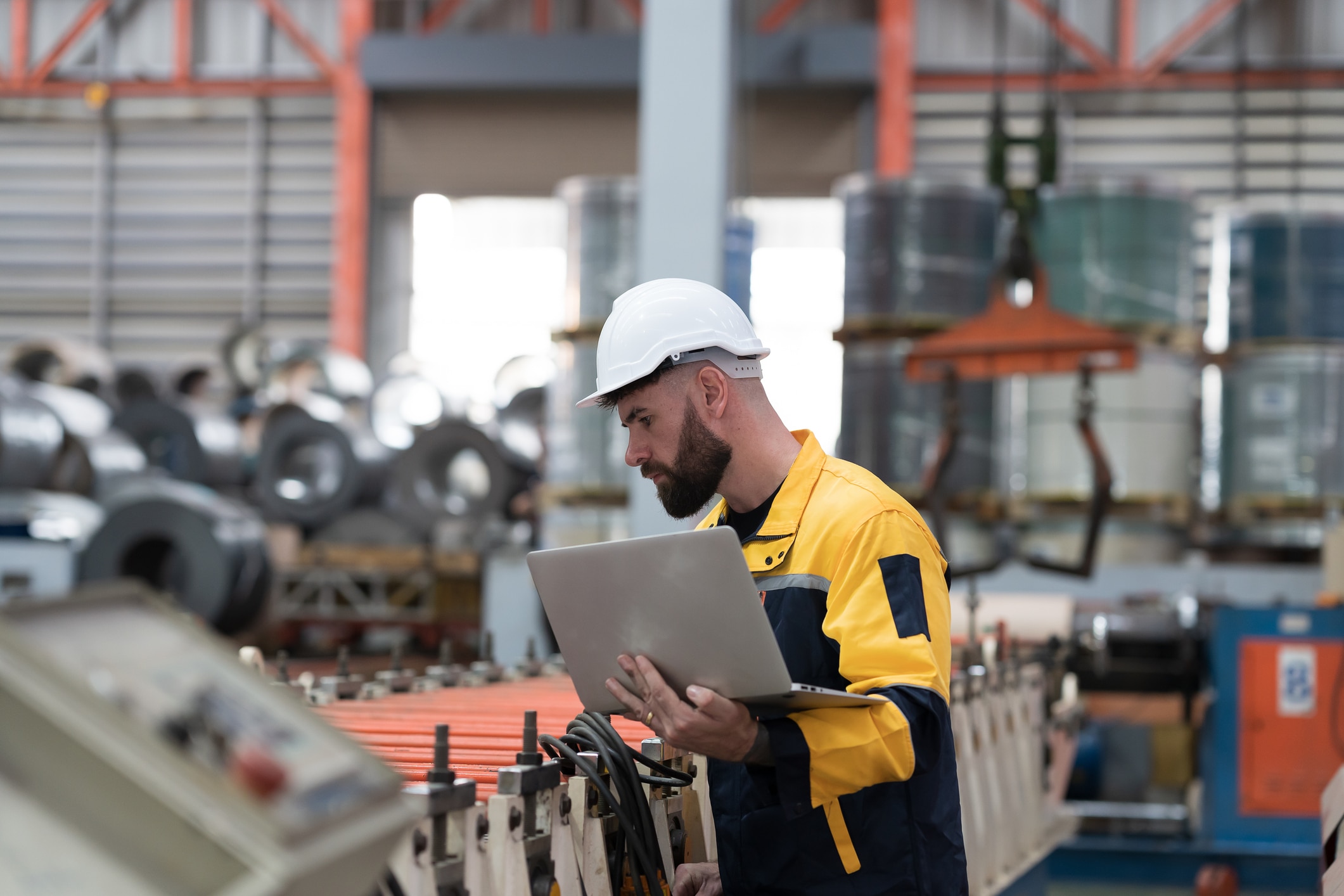 Male engineer factory worker control CNC machine by laptop computer in industry factory. Male worker working and control conveyor in manufacturing process in factory