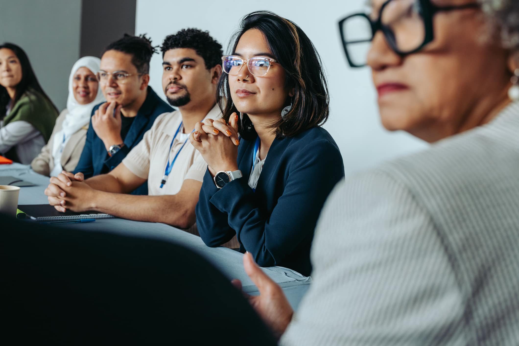 A diverse group of professionals in a boardroom meeting, focused and attentive, suggesting collaboration and teamwork.