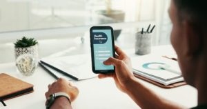 Phone, healthcare and hands of person with insurance for health, medical aid and policy. Screen, home office and worker on smartphone for online application, claims and protection on mobile app