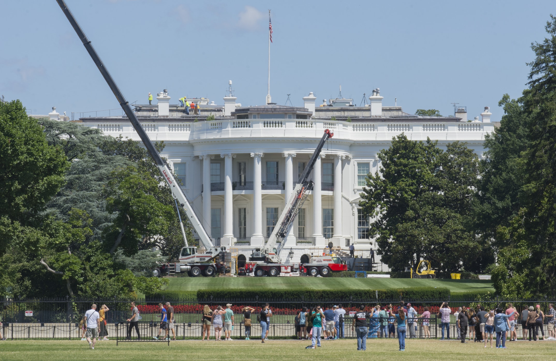 Workmen use portable construction cranes to work on the roof of the White House.