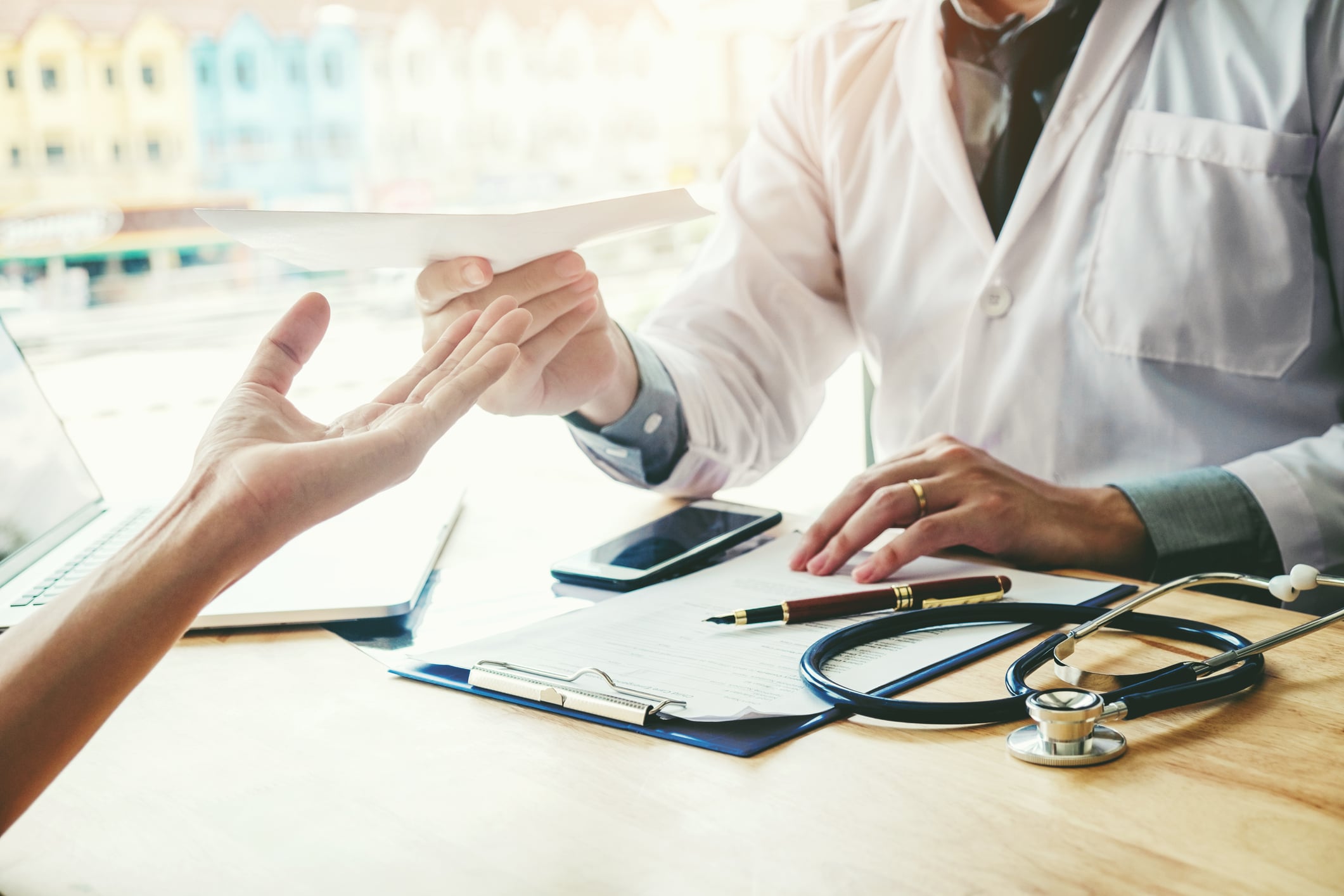 Doctor or physician writing diagnosis and giving a medical prescription to female Patient