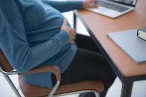 Pregnant woman using laptop at home
