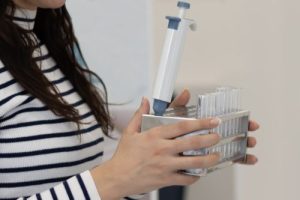 A woman carrying a plastic container sample holder for urine sample. Health care and medical concept.