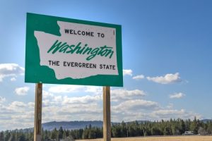 A roadside welcome to Washington the Evergreen State sign in the rural area near Spokane, Washington, USA, coming from the state of Idaho.