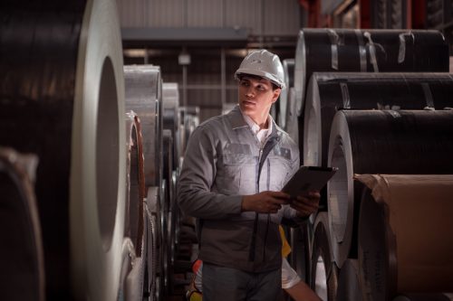 Industrial worker inspecting inside a large metal tube in a factory wearing safety helmet