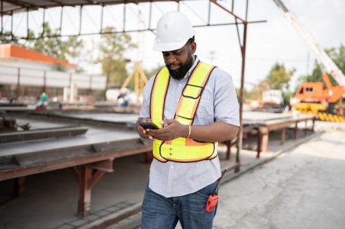 Portrait African American engineer man use smart phone with precast cement factory background