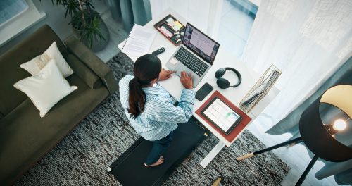 Woman, walking or typing with laptop on standing desk or treadmill above for productive day in home. Top view, female person or freelancer with computer, documents or tablet for remote work in house